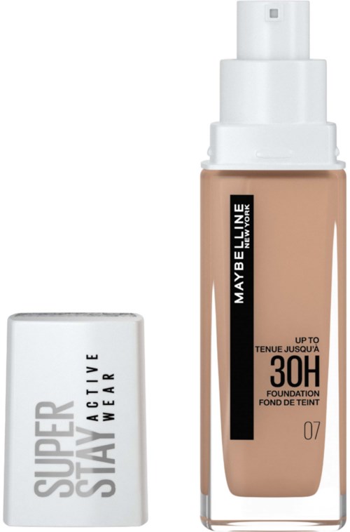 Flaska av Maybelline-foundation med pump och vit topp framför, och vit topp med svart text bakom.