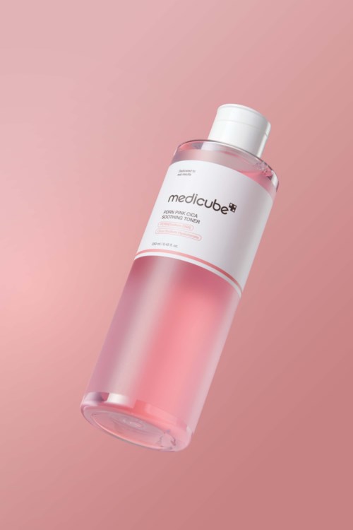 Pinkki ja valkoinen medicube-kasvovesipullo vaaleanpunaisella taustalla.