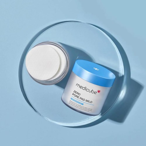 Een potje medicube Zero Pore Pad Mild op een heldere ronde schaal, met een blauwe deksel en een witte body.