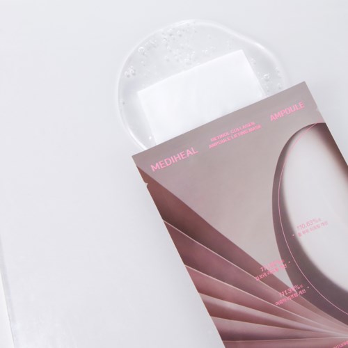 The image shows a skincare sheet mask package with pink and grey colors, placed on a white surface with some liquid around.