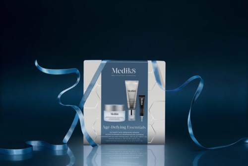 Medik8 skincare gift set with three products, decorated with blue ribbons on a reflective surface.