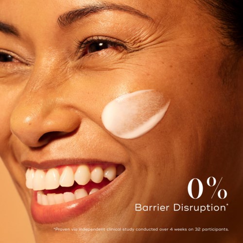 A woman smiling with a dot of cream on her cheek, promoting zero barrier disruption in skincare.