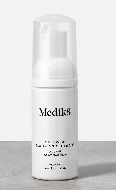 A white bottle labeled 'Medik8 Calmwise Soothing Cleanser' with a pump, designed for gentle skin cleansing.