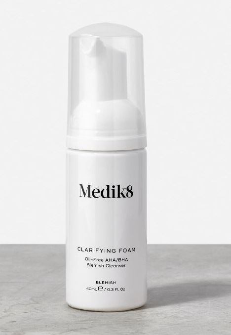 En hvit flaske merket 'Medik8 Clarifying Foam' med klar hette, brukt til rens av huden.