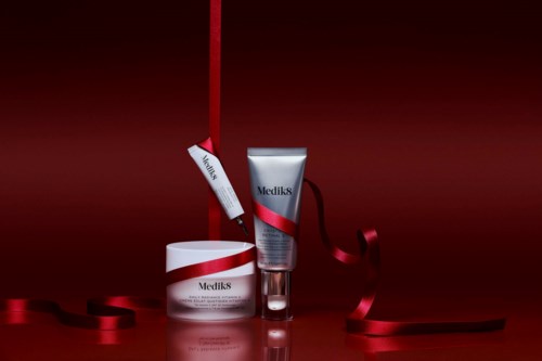 Medik8 skincare products with red ribbons and tags, set against a dark red background.
