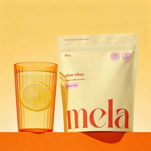 En hvit pose med proteinpulver merket Mela sitron står ved siden av et glass med sitronvann på en gul bakgrunn.