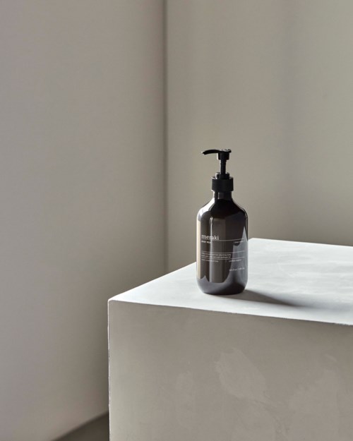 Ein schwarzer Spender für Seife oder Lotion auf einer weißen Oberfläche in der Nähe einer schlichten Wand.