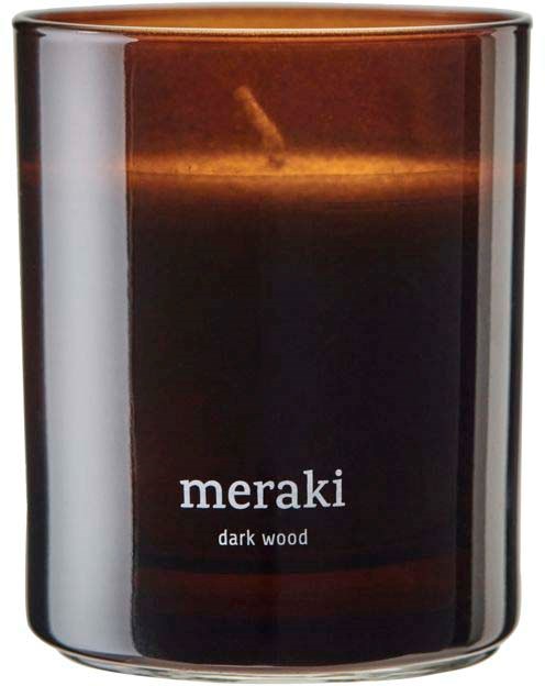 En doftljus med doft av mörkt trä i glasbehållare med enkel etikett. Det ser varmt och ombonat ut.