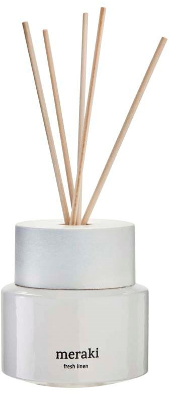 A white ceramic holder labeled "meraki" holds five thin, light wooden sticks.