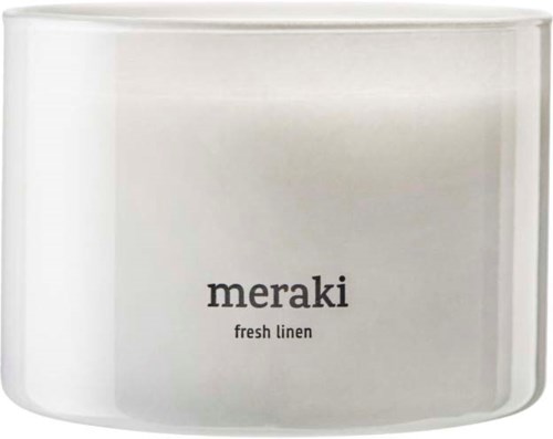 A white candle with a black label saying 'meraki fresh linen' on it.