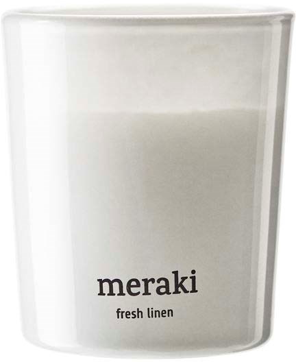 A white candle with a label saying "meraki fresh linen."