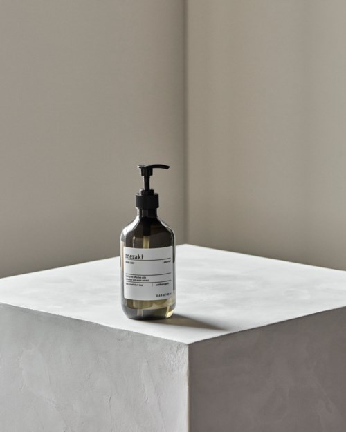 A black bottle with a pump stands on a white platform against a plain background.