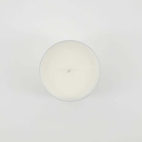 A white candle inside a clear container on a plain background.