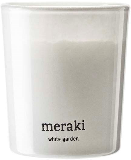 Eine weiße Kerze mit einem schwarzen Etikett, auf dem "meraki" und "white garden" steht.
