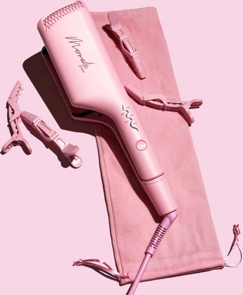 Roze föhn, stijltang en een plat gereedschap op een roze mat. Alle tools worden voor haarstyling gebruikt.