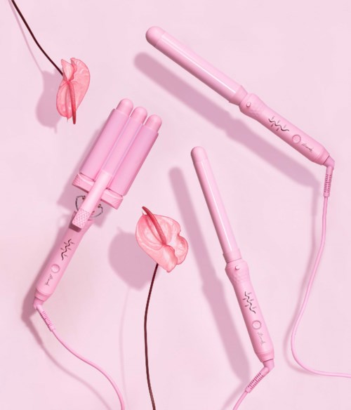 Pink hair curling irons with a flower and a light pink background.