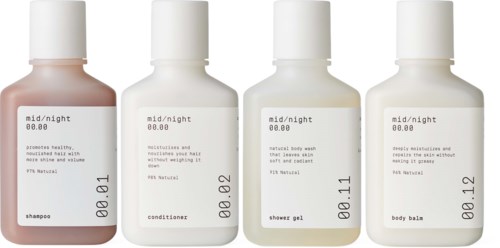 Four small white bottles labeled for shampoo, conditioner, shower gel, and body balm with simple text.