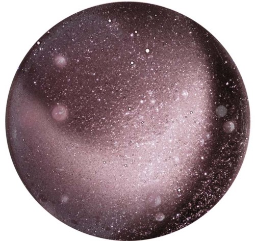 A round image showing a star-filled sky or galaxy with many bright points and cosmic dust.