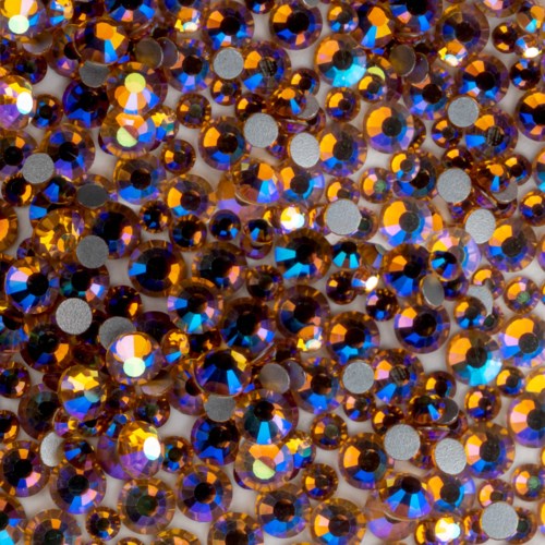 Many small, shiny, brownish-orange rhinestones with reflective, multicolored surfaces clustered together.