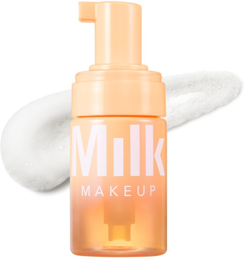 En persikfärgad flaska märkt 'Milk Makeup' med pump, jämn kräm eller lotion bredvid.