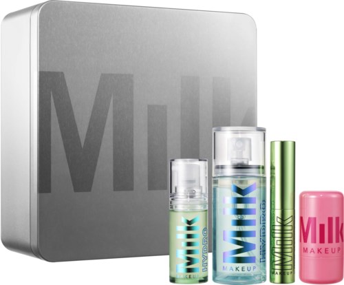 En uppsättning Milk Makeup hudvårdsbehållare framför en silver Milk Cosmetics-box med sprayflaskor, en stång och en bar.