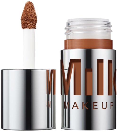 Een make-up staaf met een bruin fundament en een glanzend zilveren container met grote letters.