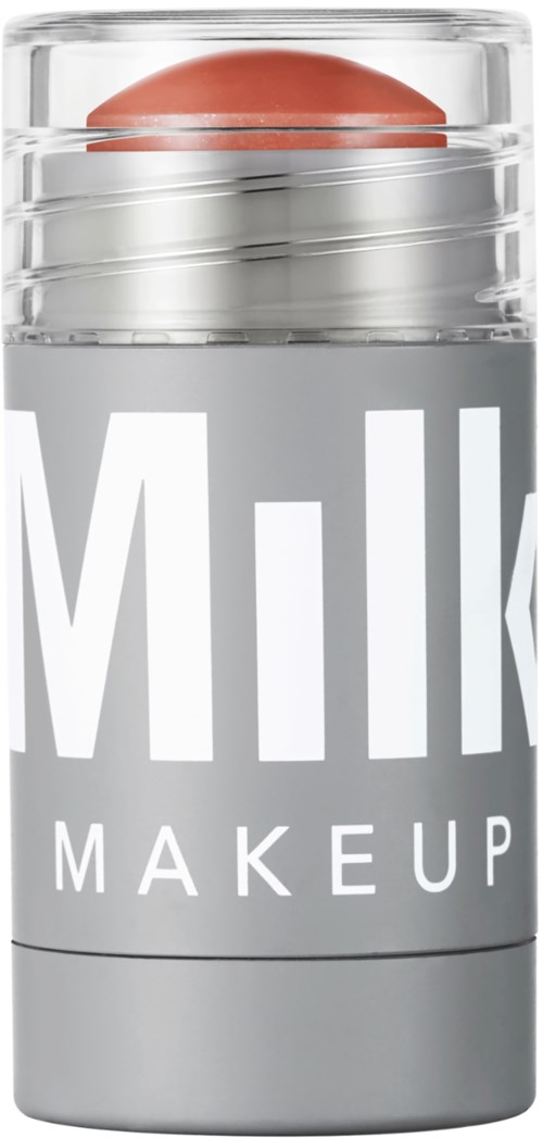 Een kleine, doorzichtige container met deksel, gemerkt "Milk Makeup," met een roze-bruin ei-vormig voorwerp.