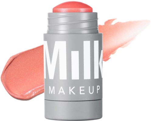 Een roze make-upstift in een zilveren houder met het woord 'MILK' erop, en een roze kleurstaal op de achtergrond.
