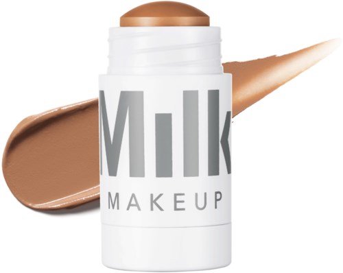 Ein Make-up-Produkt mit der Bezeichnung "Milk" in einem weißen Behälter, mit beigecreme oder Foundation, die herausläuft.