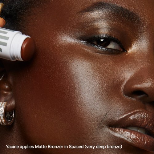 Yacine brengt Matte Bronzer in Spaced, een heel donker brons, aan op haar gezicht.