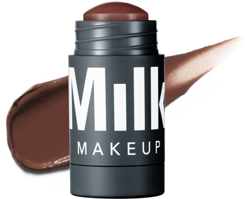 A stick of brown makeup, labeled 'Milk Makeup,' with some swiped on skin behind it.