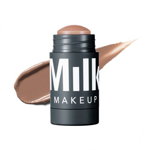 Een container met 'Milk Makeup'-label en een beige product, met een staal op witte achtergrond.