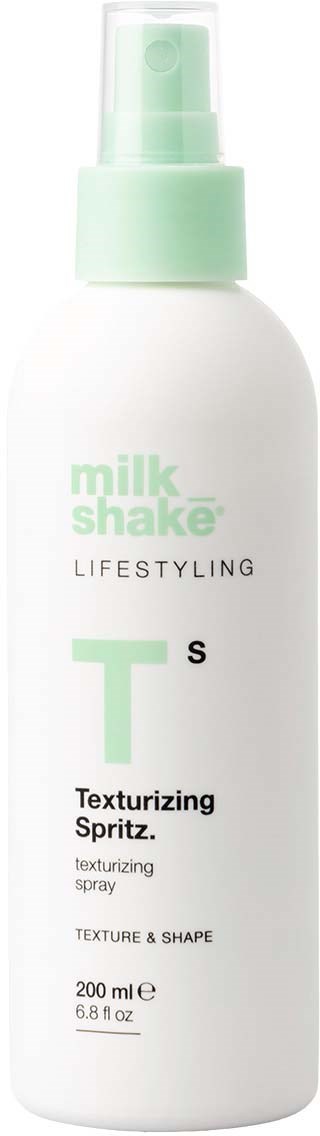 Een witte fles met een groen deksel, gelabeld als Milk Shake Lifestyle Texturizing Spray voor textuur en vorm.