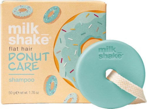 A turquoise round shampoo bar with a hole and a rope, in front of a box featuring a donut and sprinkles design.