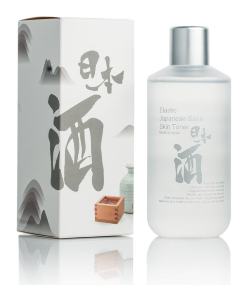 Een huidverzorgingsfles en doos met Japanse tekens, gelabeld 'Elastic Japanese Sake Skin Toner', samen met een klein houten voorwerp.