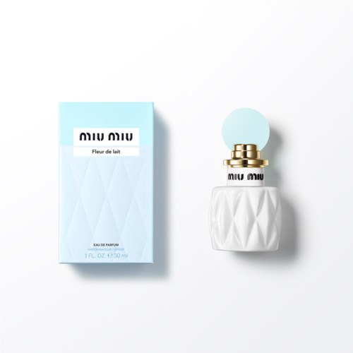 Een parfumfles en doos. De doos is lichtblauw met witte en zwarte tekst. De fles is wit met gouden details.