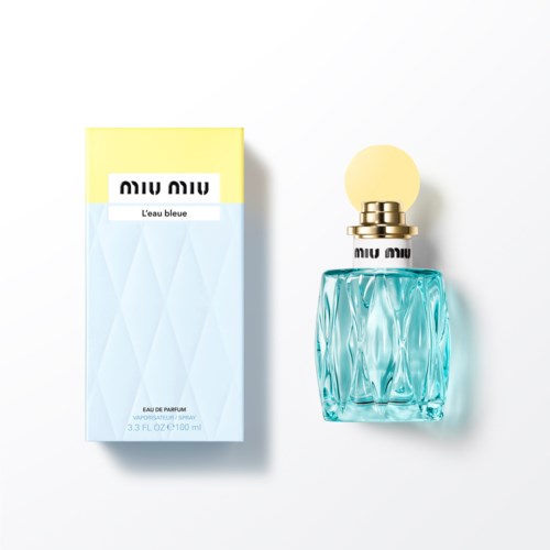 Een parfumfles en verpakking voor "Miu Miu L'eau Bleue." De fles is blauw met een ronde, gele dop.