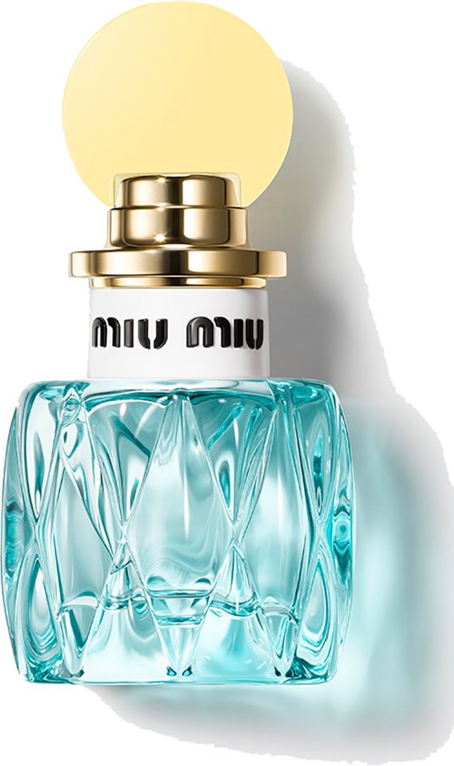 Een parfumfles met een turquoise glazen basis en een witte en gouden dop. De dop heeft een gele bal bovenop.
