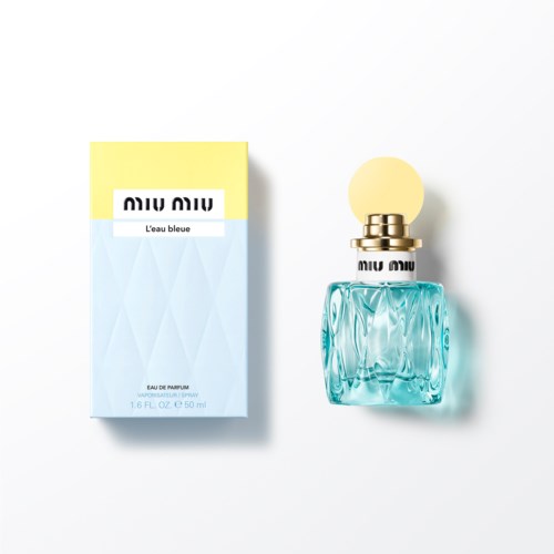 Een parfumfles naast de doos met geel, blauw en wit, genaamd "L'eau bleue."