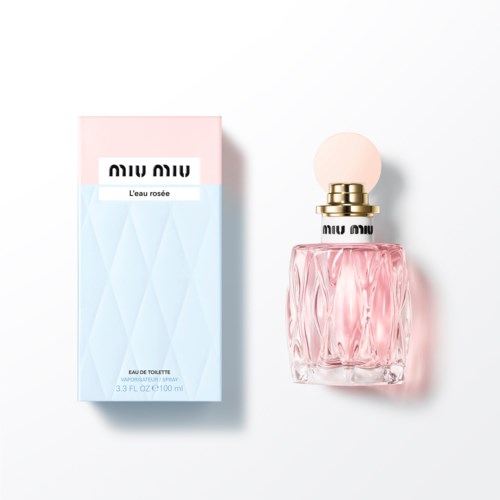 Roze parfumfles met een ronde off-white dop naast de pastel roze en blauwe doos.