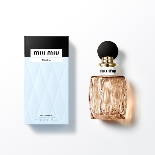 Een fles parfum naast de doos, beiden elegant met een roze fles en zwarte en witte verpakking.