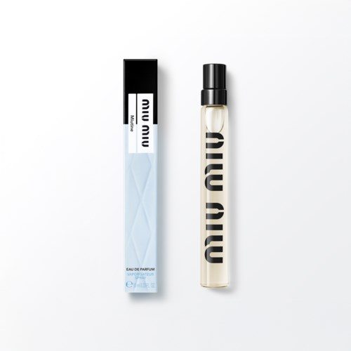 Een parfumfles met een zwart deksel en "Miu Miu" geschreven in het verticaal, naast de doos.