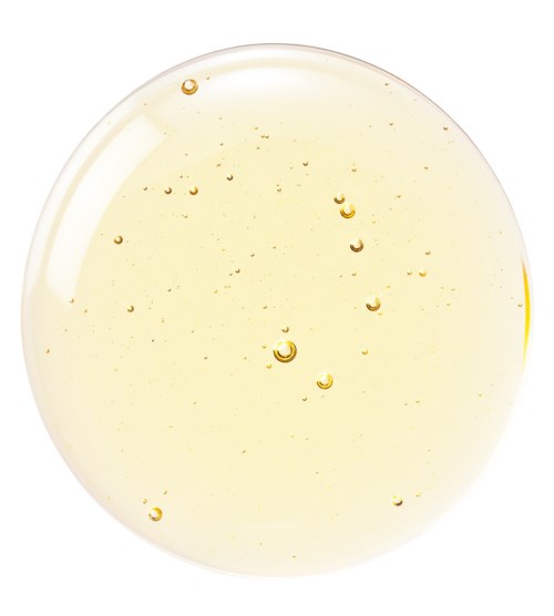 En rund glas med en ljusgul, bubblig vätska inuti, med små bubblor som flyter omkring.