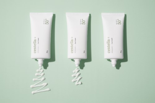 Drie witte tubes met roomachtige spiraalontwerpen, gemarkeerd 'centella', op een lichtgroene achtergrond.