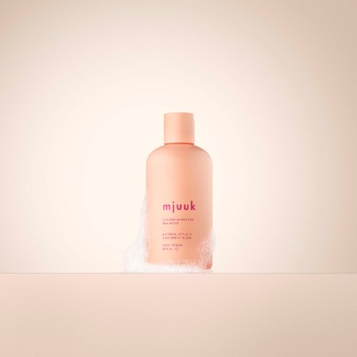 Roze fles met schuim rondom de onderkant, op een eenvoudige lichte achtergrond.