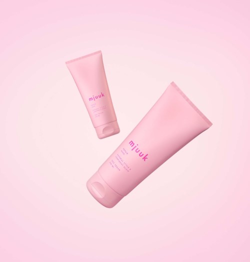 Twee roze tubes, een grote en een kleine, met het label "miuuk," zwevend op een roze achtergrond.