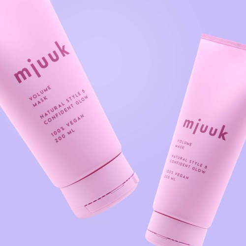 Twee roze tubes met "mjuuk"-label en details over volume en voordelen. Ze staan tegen een pastelachtergrond.