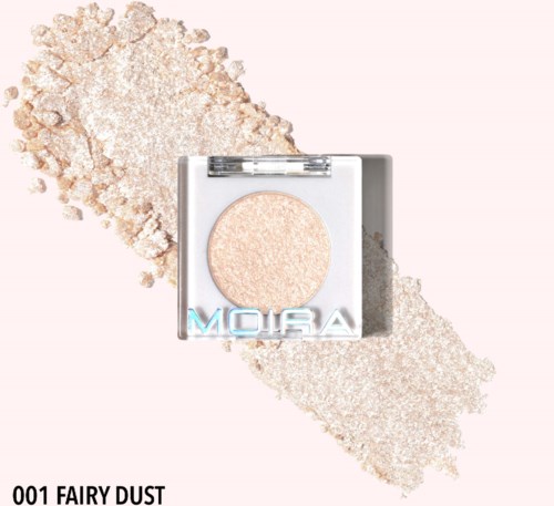 A pressed powder makeup with the name 'Fairy Dust' on packaging, surrounded by loose powder. Light sparkly color.