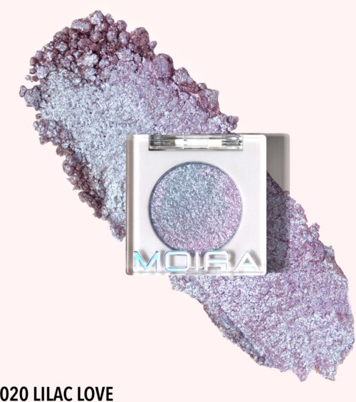 A shiny purple eyeshadow compact with the word "Moira" and "020 Lilac Love" beneath. Background has purple glitter.