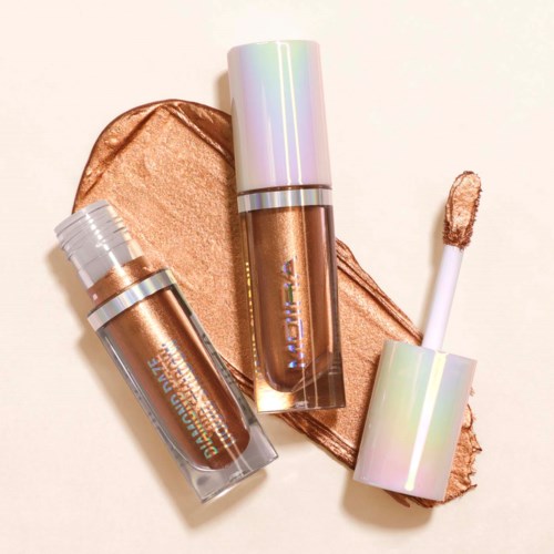 Zwei irisierende und metallische flüssige Highlighter mit Applikatoren, einer mit hell und einer mit Bronze-Farbe, auf einem glitzernden Bronze-Hintergrund.